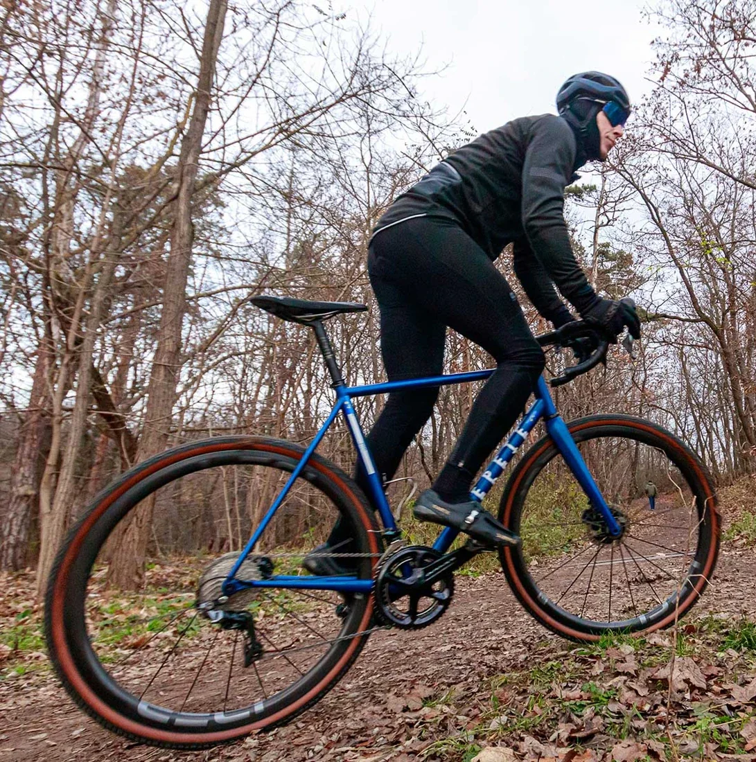 A gravel bike with IDEA ROUBAIX wheels riding through a forest