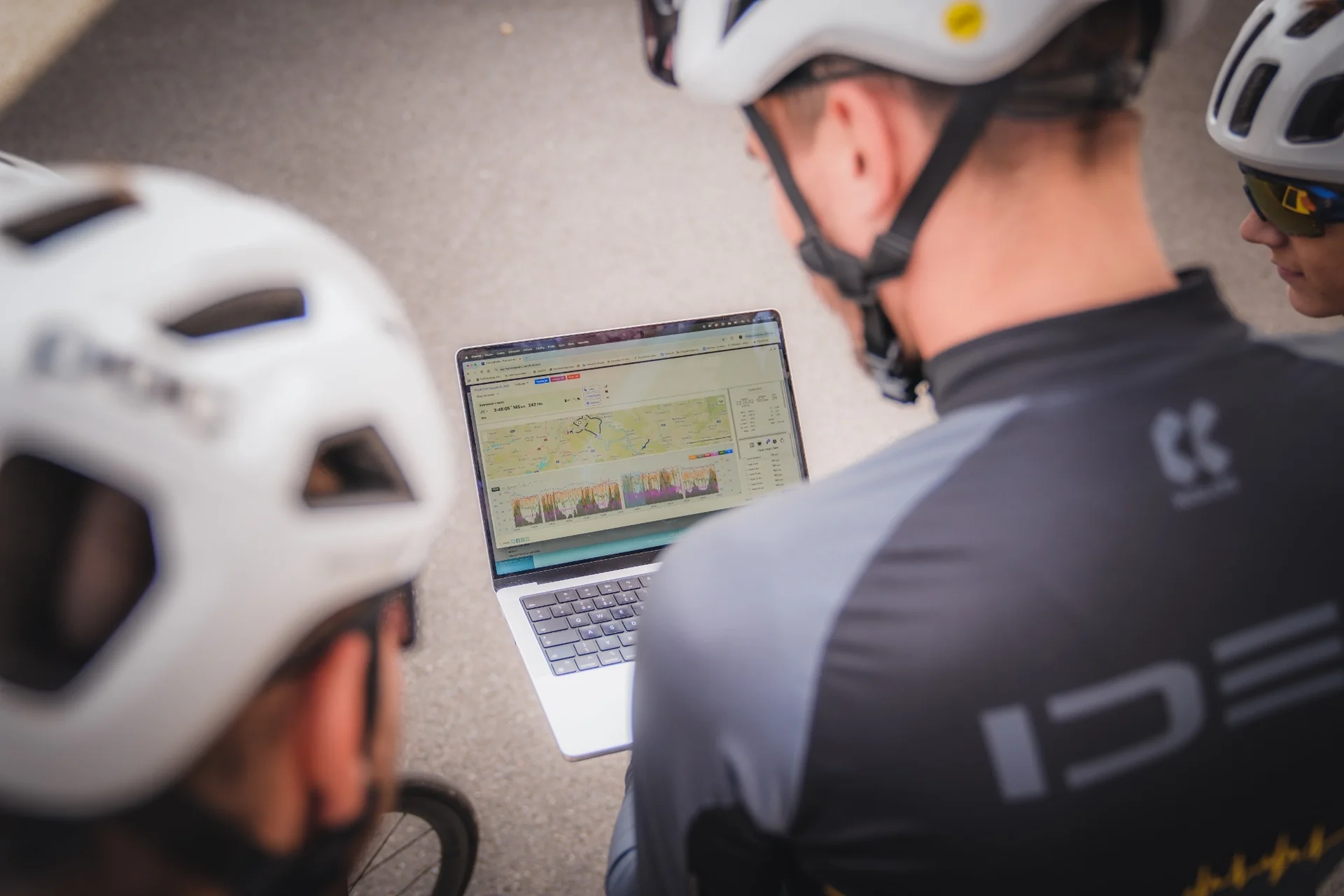Team members in cycling helmets reviewing a training session on a laptop